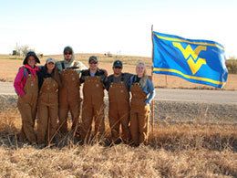 Students in coveralls with WVU flag