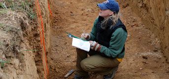 image of student in pit examining soil